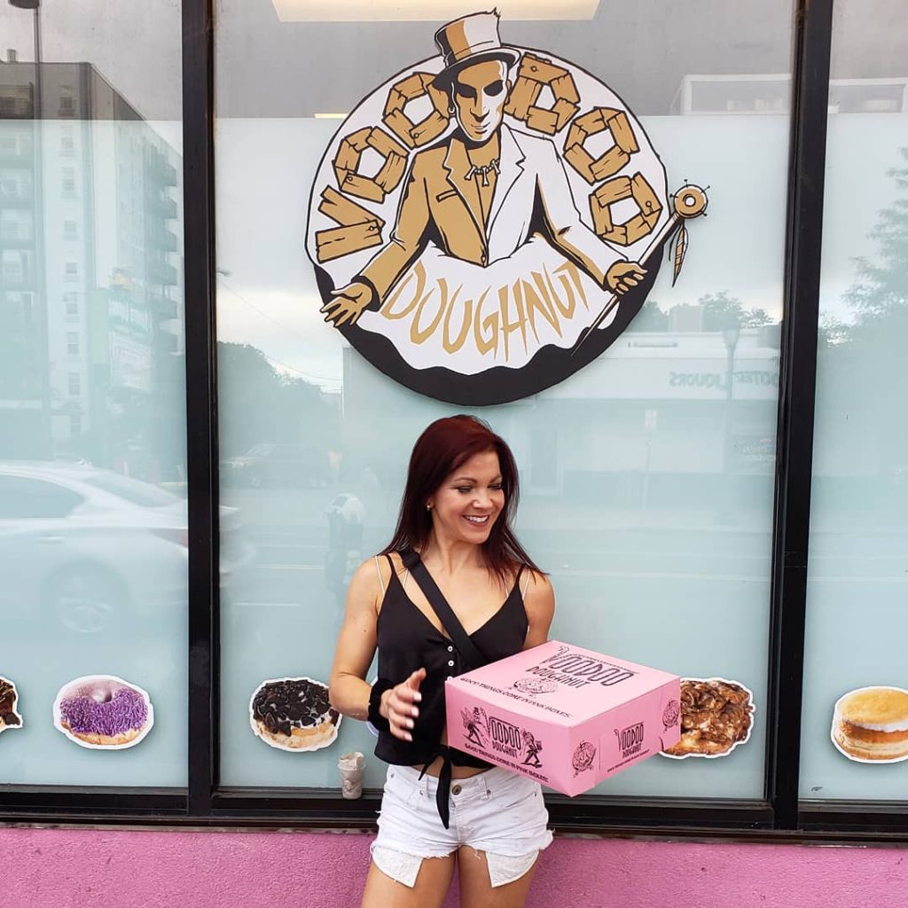 Erin Good outside of Voodoo Doughnut with a pink box